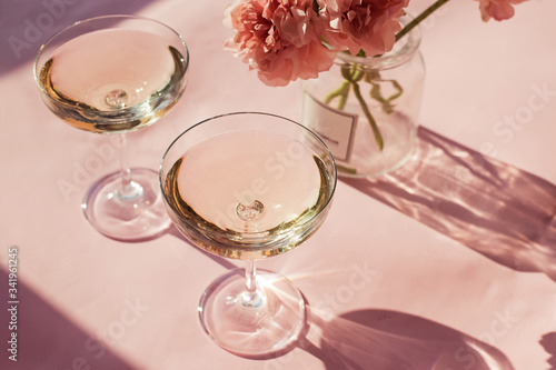 Two glasses of sparkling wine on a pink table