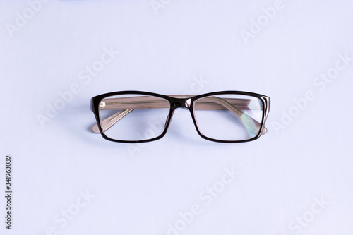 Classic glasses in a black rectangular frame were shot close-up and flat lay on a light background. There is a place for text. The photo was made with love for your design.