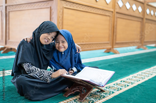 happy muslim asian kid smiling during reading quran together at the mosque