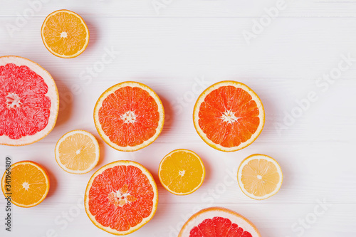 Halves of fresh orange and grapefruit citrus fruits on white wooden background