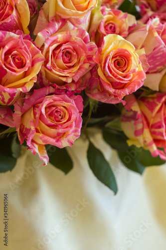 A bouquet of pink flowers. White fabric, beige fabric, plain fabric. Two-tone roses, pink and yellow roses