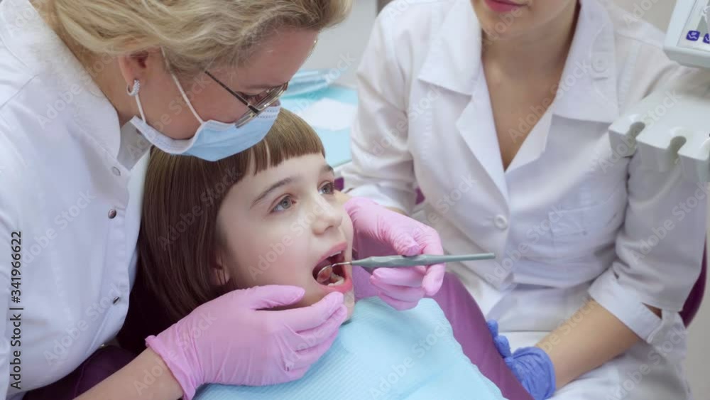 Dentist examines little girl's oral cavity Dentist examines little girl's oral cavity
