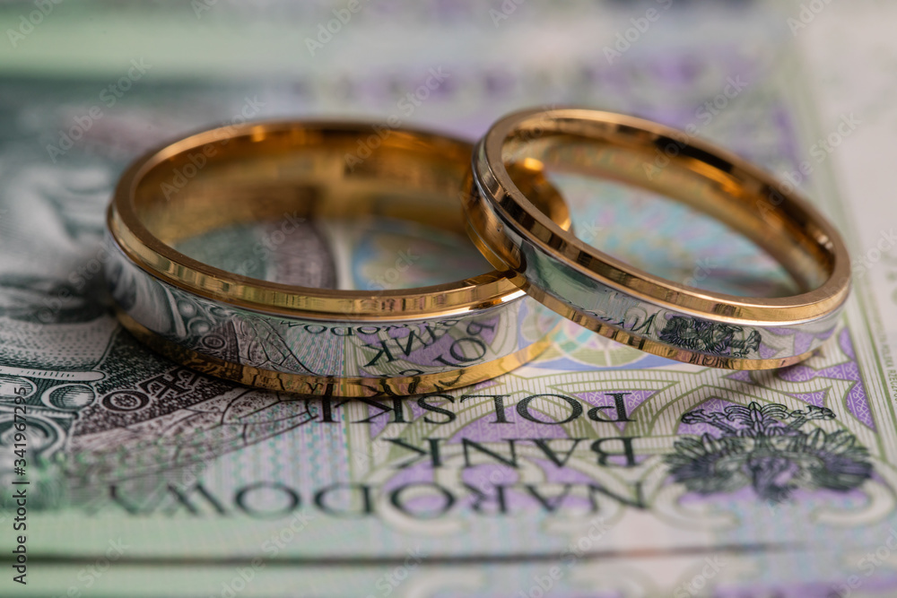 Gold wedding rings surrounded by a stack of Polish banknotes. Gold wedding rings surrounded by a stack of Polish banknotes.