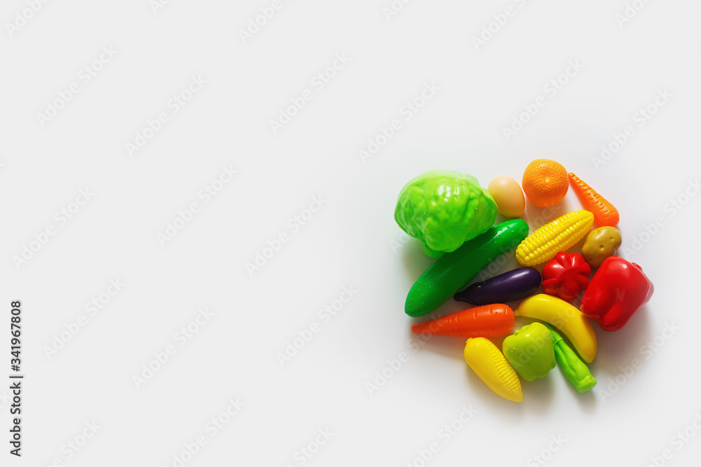 Still life with the image of colorful plastic children's fruit and vegetable toys on a white background. Top view with copy space. Still life with the image of colorful plastic children's fruit and vegetable toys on a white background. Top view with copy space.