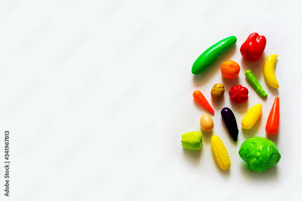 Still life with the image of colorful plastic children's fruit and vegetable toys on a white background. Top view with copy space. Still life with the image of colorful plastic children's fruit and vegetable toys on a white background. Top view with copy space.