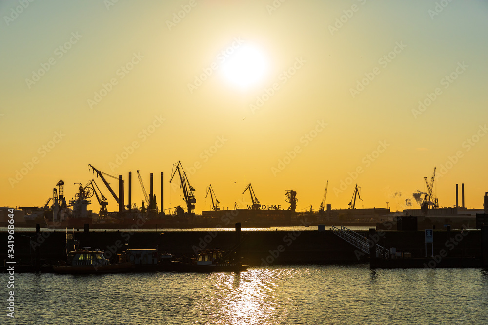 Beautiful sunset in harbour, port, industrial landscape with ships and crans