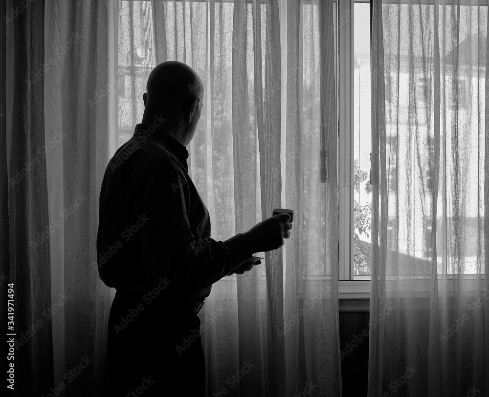 Hombre mira por la ventana de un edificio durante el confinamiento por el coronavirus COVID-19. La prohibición de salir a la calle es el origen de problemas de soledad y depresión en muchas personas.