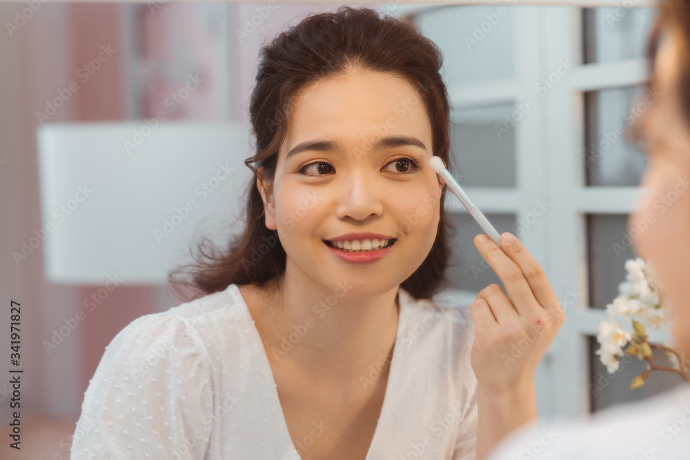 Eye makeup woman applying eyeshadow powder. Young beautiful woman making make-up near mirror, sitting at the desk