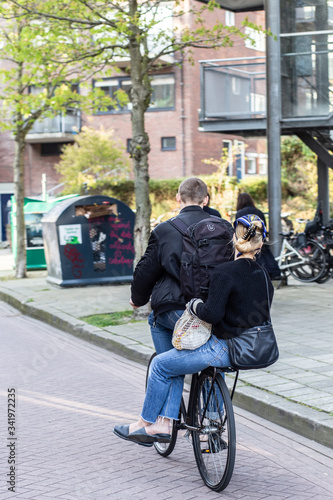 Canvas Print Two persons riding a bicycle on a city street of Amsterdam (the Netherlands)