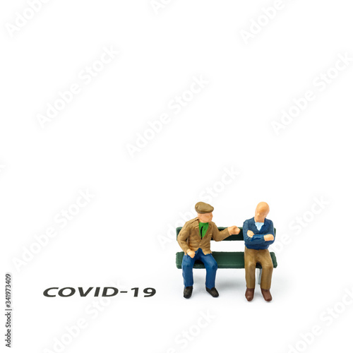 Two old men and coronavirus outbreak. Small figurines and text about Covid-19 on white background.