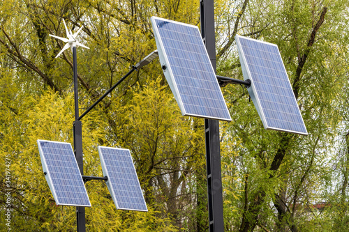 Street electricity by small windmill and solapanels in the city against buildings in daytime. Concept of newable, eco or environmentally friendly and clean energy.