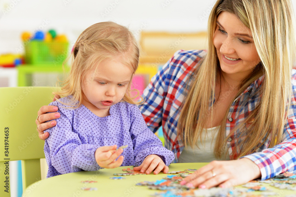 Portrait of mother with little daughter collecting puzzle Portrait of mother with little daughter collecting puzzle