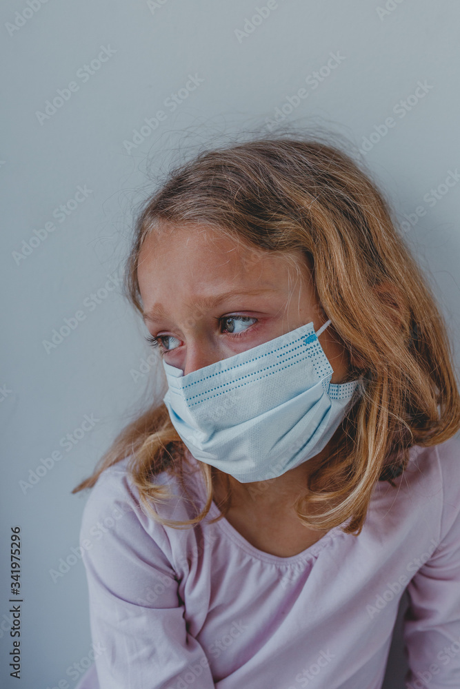 a sad girl in quarantine with a mask looks with blue eyes. portrait close-up. covid a sad girl in quarantine with a mask looks with blue eyes. portrait close-up. covid