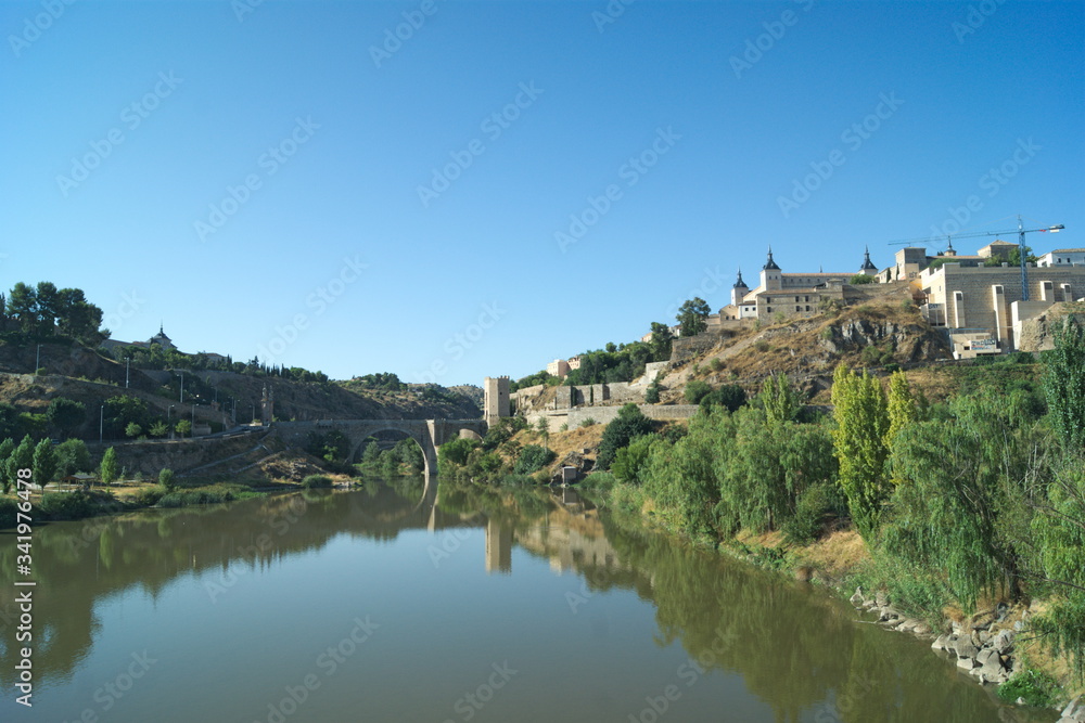 Spain, Toledo, the beautiful, historic Alcantara bridge.  The monument is reflected in the still  waters of the river Tagus.