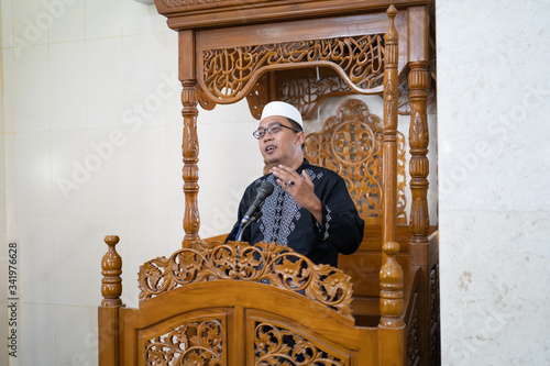 portrait of muslim male preacher sharing about islam during prayer time in the mosque photo