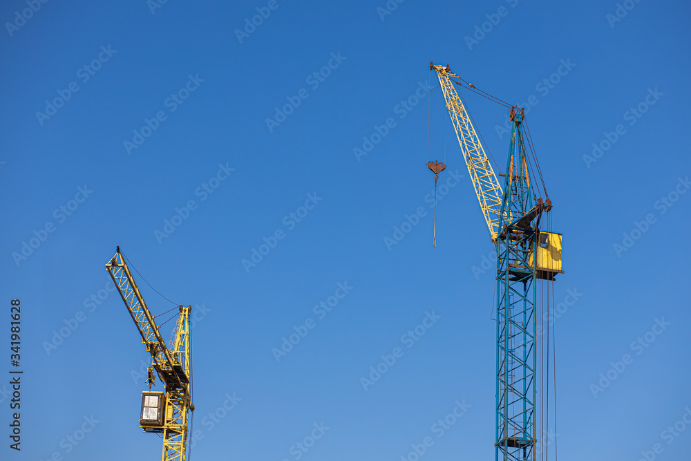 Industrial construction cranes on a blue background, idle cranes Industrial construction cranes on a blue background, idle cranes