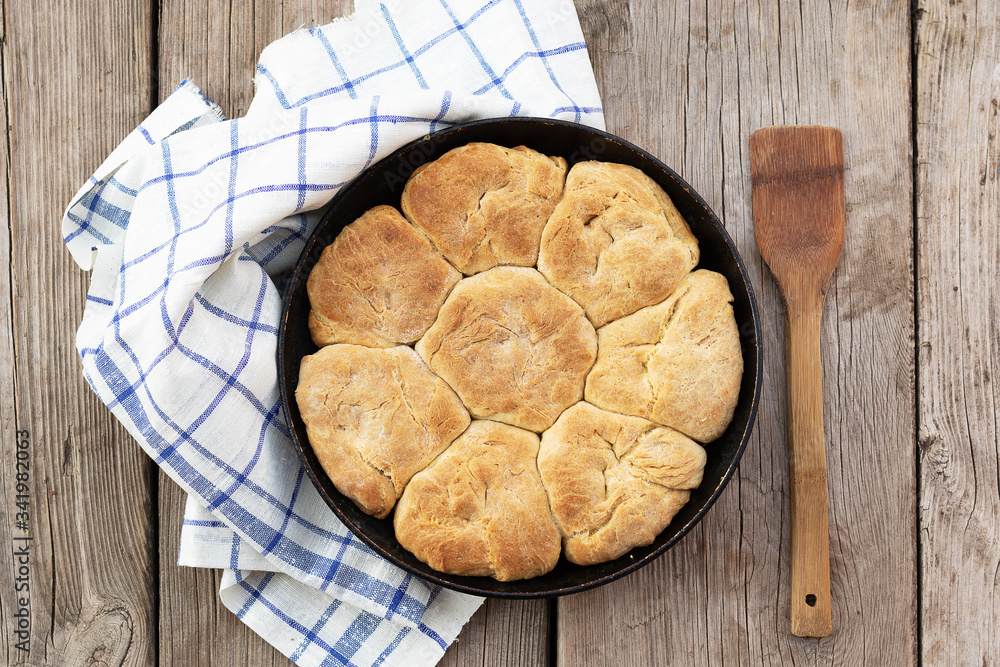 Fresh homemade wholemeal bread in metal baking dish. Wooden background, fabric napkin and spatula lie nearby Fresh homemade wholemeal bread in metal baking dish. Wooden background, fabric napkin and spatula lie nearby