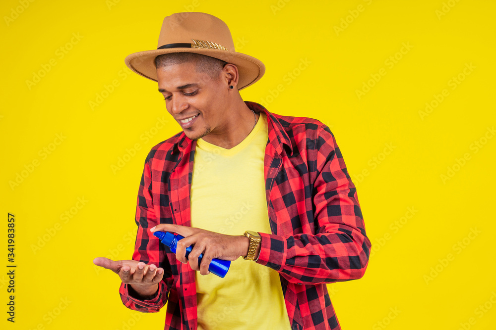 afro brazilian man choosing spf bottle in studio yellow wall afro brazilian man choosing spf bottle in studio yellow wall