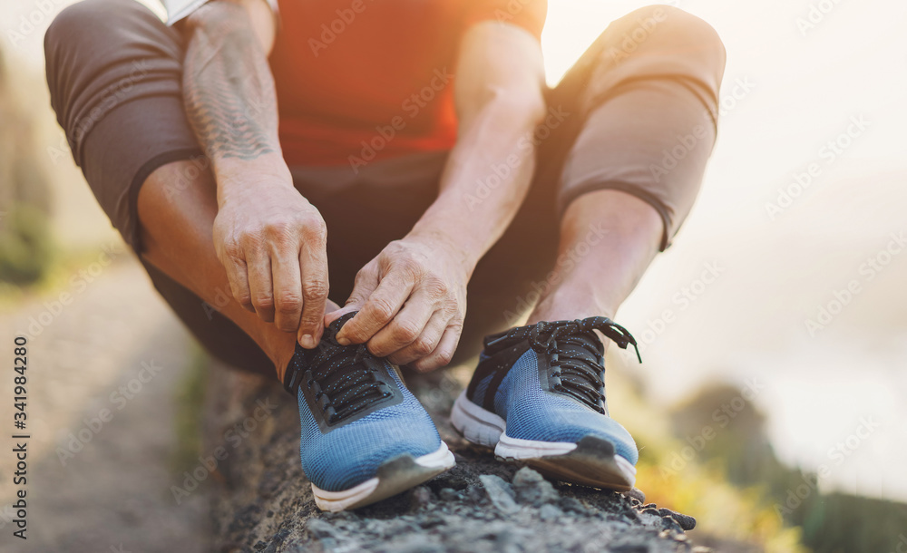 Fit tattoo man tie his sport shoes outdoor during jogging session