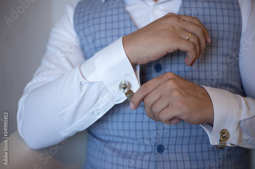 man fastens cufflinks on a shirt © Katherine