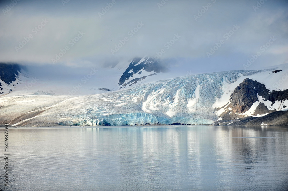 A glacier creeps from the mountains into the sea water. A glacier creeps from the mountains into the sea water.