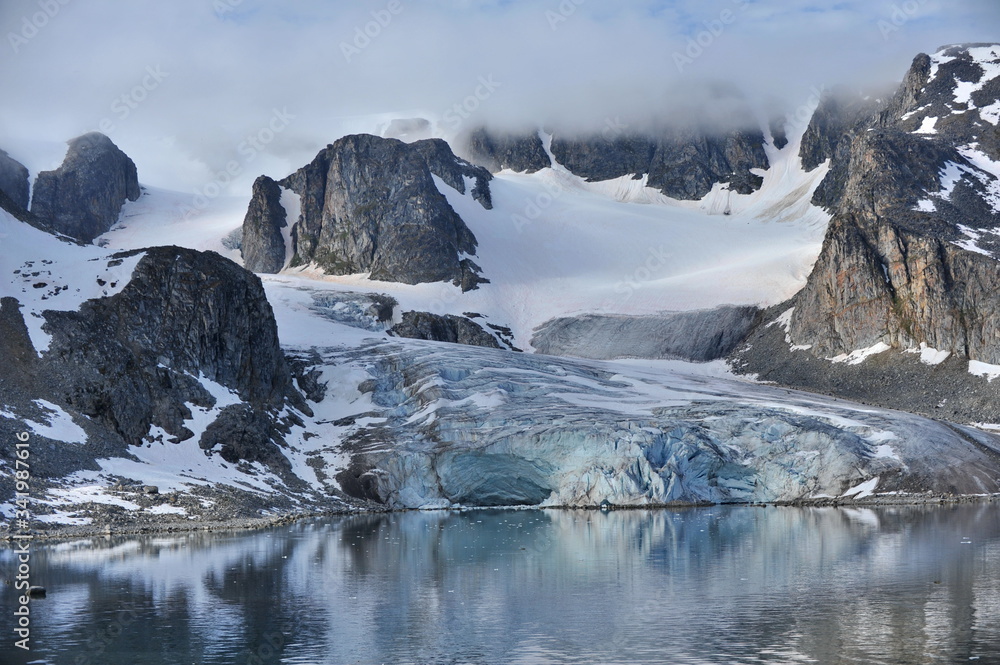 A glacier creeps from the mountains into the sea water.