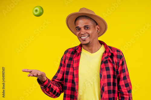 latin hispanic farmer showing a green apple in studio yellow background