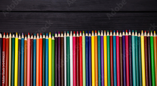 Colored pencils of all colors of the rainbow are on the black table