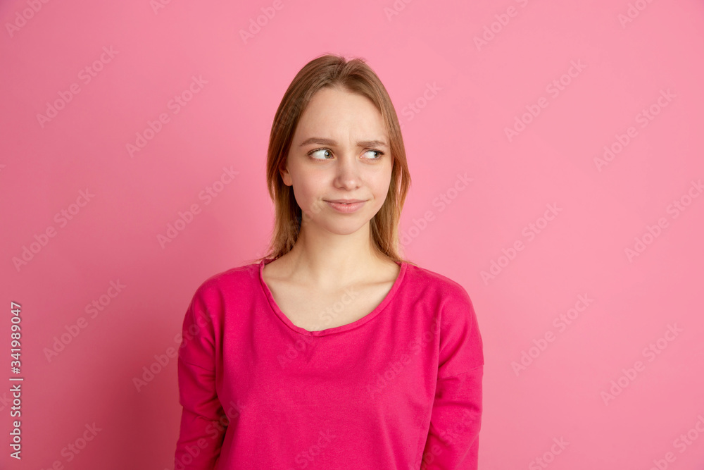 Doubt, uncertainty. Caucasian young woman's portrait isolated on pink studio background, monochrome. Beautiful female model. Concept of human emotions, facial expression, sales, ad, trendy. Doubt, uncertainty. Caucasian young woman's portrait isolated on pink studio background, monochrome. Beautiful female model. Concept of human emotions, facial expression, sales, ad, trendy.