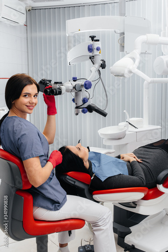 The dentist looks through a microscope and performs surgery on the patient