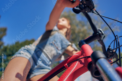blurred teenage girl on the bicycle, blue sky. The view from the bottom. Close-up.
