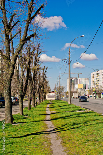 traffic on a city street on a sunny day against a blue cloudy sky and houses