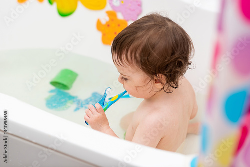A one-year-old baby washes in the bathtub, plays with toys, learns to brush his teeth.