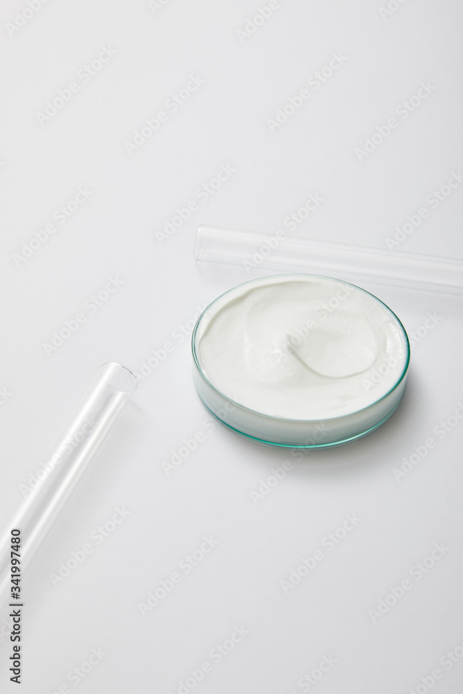 Laboratory glassware with white cosmetic cream and test tubes on grey background Laboratory glassware with white cosmetic cream and test tubes on grey background