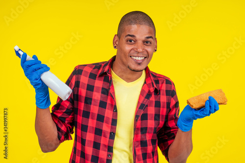 latin brazilian cleaning man wearing ribon gloves in studio yellow background