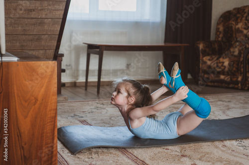Foto Little cute girl is practicing gymnastics at home