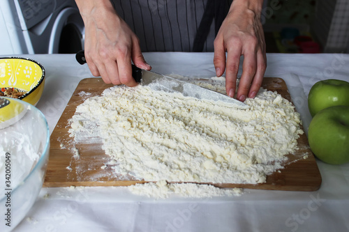 The cook's hands chop butter and flour on a wooden Board with a knife. Homemade cake. Housework.