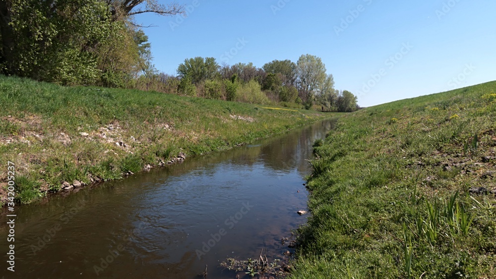 View of artificial water channel connecting dead river channel with river, spring daylight sunshine. 