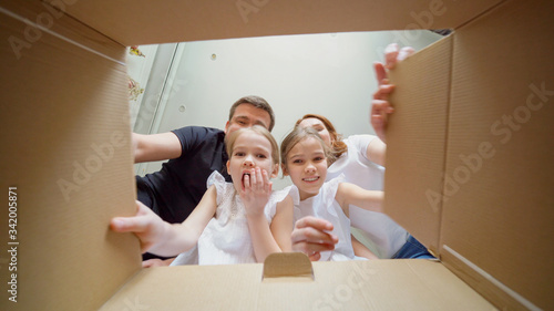 Mom, dad and daughters looks in the box, surprise