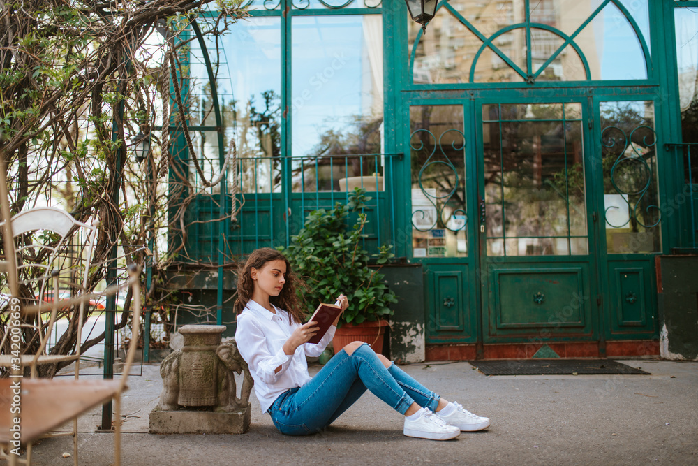A beautiful young caucasian girl is reading a book in the garden. Spring and flowers A beautiful young caucasian girl is reading a book in the garden. Spring and flowers