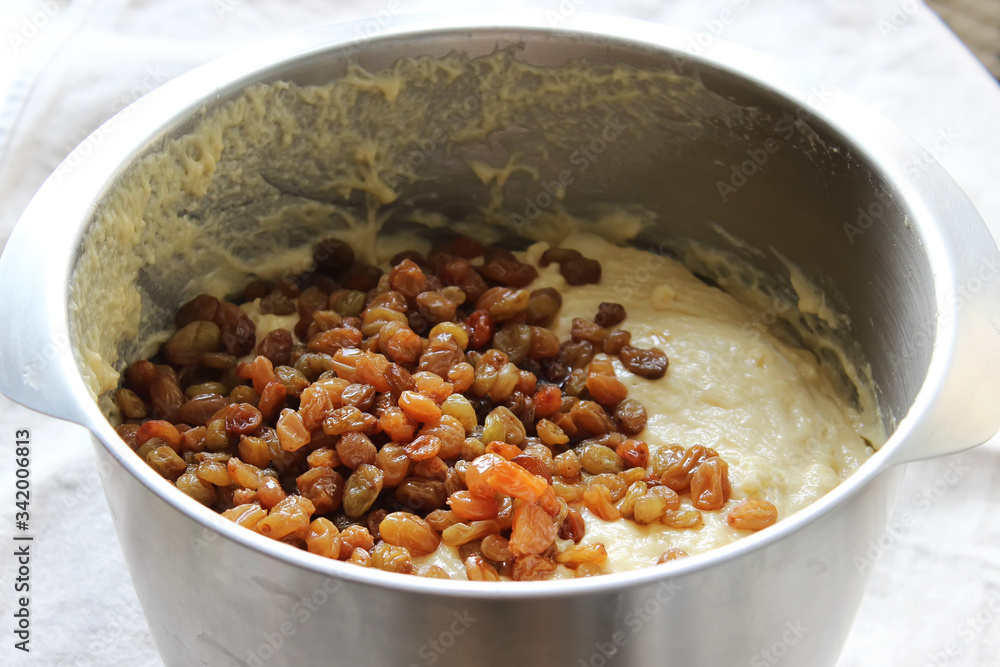 Raisin muffin dough in a large metal bowl. Homemade cake. Concept of homework during the quarantine period. Raisin muffin dough in a large metal bowl. Homemade cake. Concept of homework during the quarantine period.
