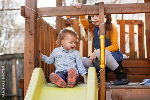 Children ride slide on wooden playground together