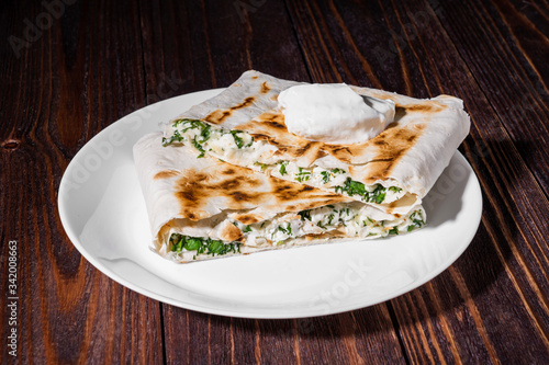 cannelloni, cottage cheese with greens in pita bread on a plate