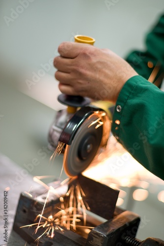 Worker cutting metal hand work angle grinder sparks.