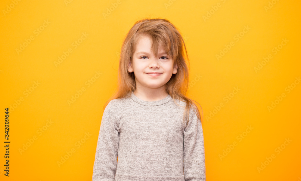 Portrait of smiling little girl in grey dress over yellow background. Portrait of smiling little girl in grey dress over yellow background.