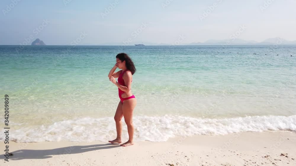 Girl brunette walks on the beach of an uninhabited island with azure water Girl brunette walks on the beach of an uninhabited island with azure water