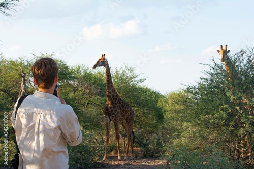 Tourist on the bush with giraffe on the background.