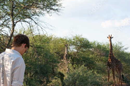 Tourist on the bush with giraffe on the background.