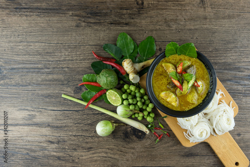 Green curry (Kaeng kheiyw hwan) with Thai food for steamed rice or rice noodles. chicken green curry is thai food very popular on dark wooden background. top view