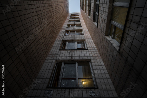 Bottom-up view of a multi-storey Soviet apartment building, an old abandoned house in a poor neighborhood at dusk.